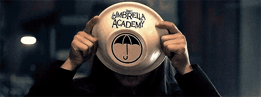 a person holding a plate that says the umbrella academy on it