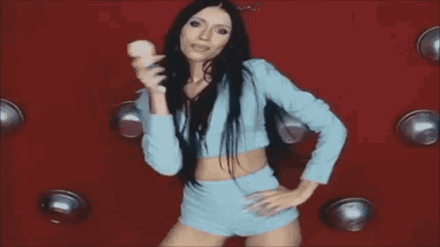 a woman in a blue crop top and shorts is holding a microphone .