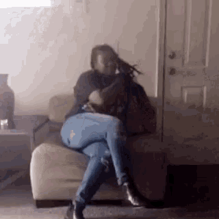 a woman is sitting on a couch in a living room holding a gun .