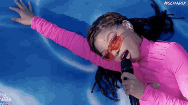 a woman in a pink shirt is singing into a microphone with the word mocha on the bottom