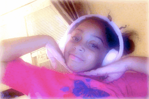 a young girl wearing headphones and a pink shirt with a butterfly on it
