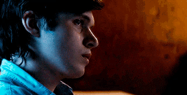 a close up of a young man 's face with a blue shirt on