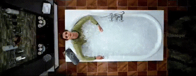 a man is laying in a bathtub with flamingoer written on the bottom right