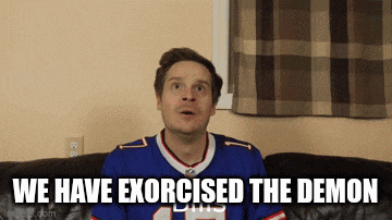 a man in a buffalo bills jersey is sitting on a couch with the words " we have exorcised the demon " above him