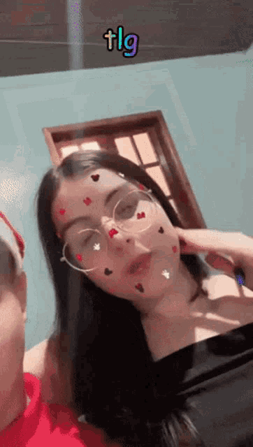 a woman wearing glasses has hearts on her face and the word tlg is above her head