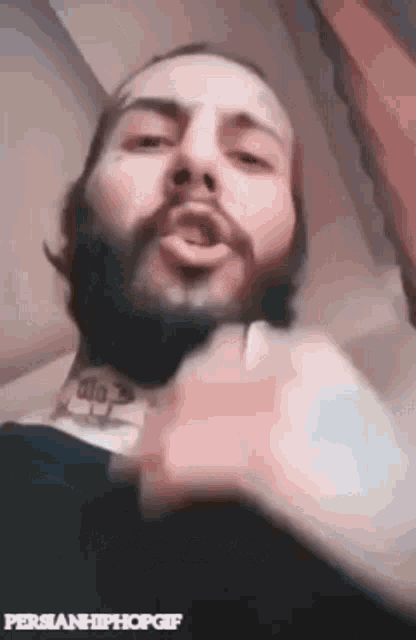 a man with a beard and a tattoo on his neck is talking .