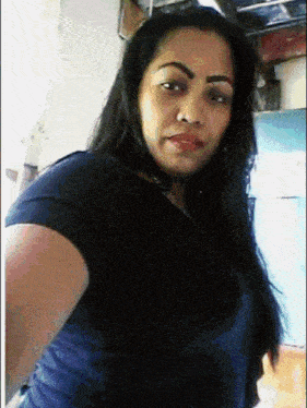 a woman in a blue shirt is taking a picture of herself
