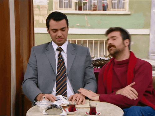 two men are sitting at a table with a newspaper on it that says ' istanbul '