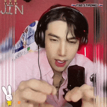 a young man wearing headphones and a pink shirt with the word jin written on it