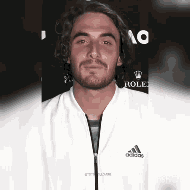 a man with a beard wearing a white adidas jacket
