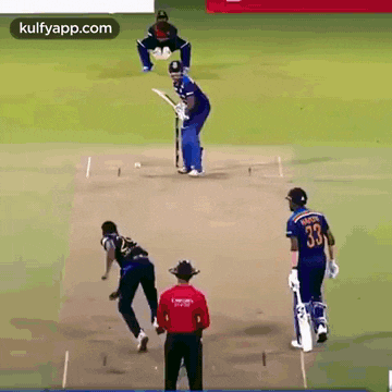 a group of cricket players are playing a game of cricket on a field with a referee .