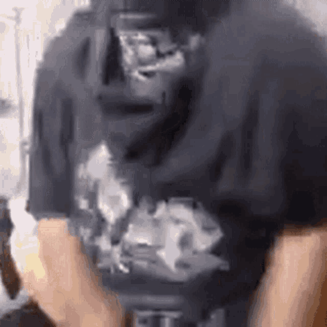 a man wearing a black t-shirt with a picture of a gorilla on it is holding a banana .