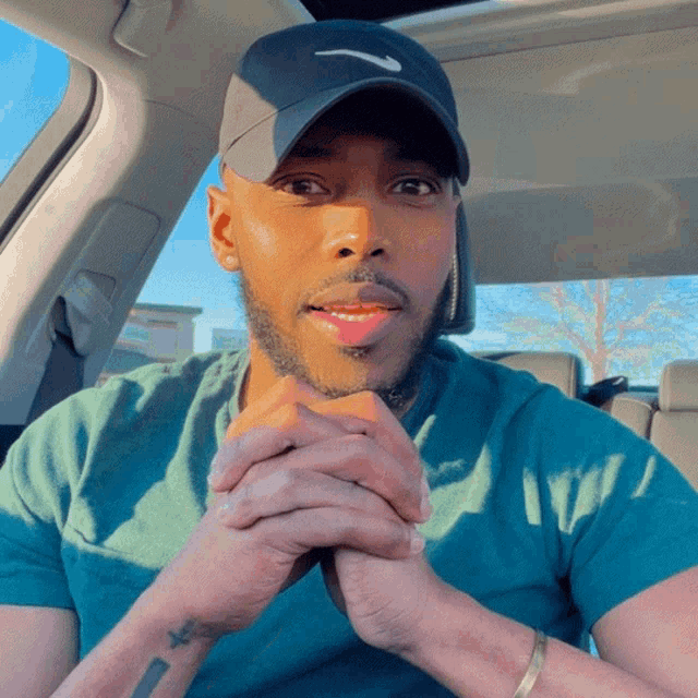 a man wearing a nike hat is sitting in the back seat of a car
