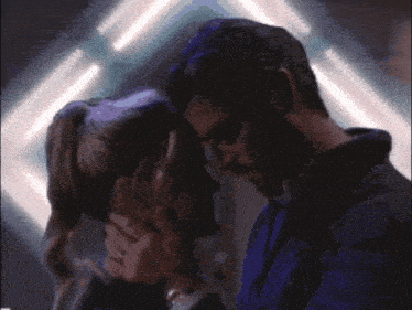a man and a woman are touching their foreheads in a dark room