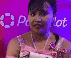 a woman in a pink dress is making a funny face in front of a pink and purple background .