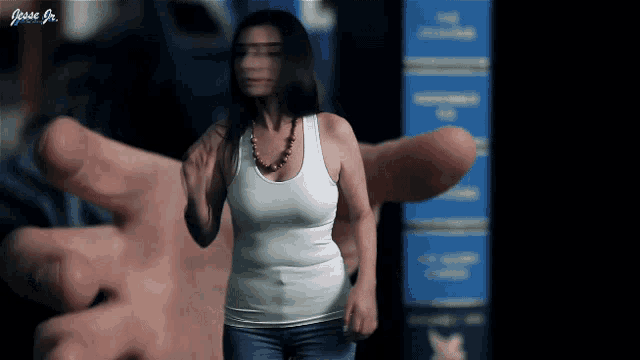 a woman in a white tank top is being held by a large hand with the name jessie jr. on the bottom right