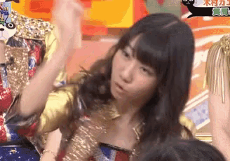 a woman in a gold dress is dancing in front of a crowd .