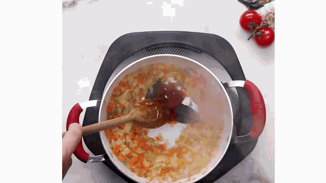 a person is stirring a pot of food with a wooden spoon .