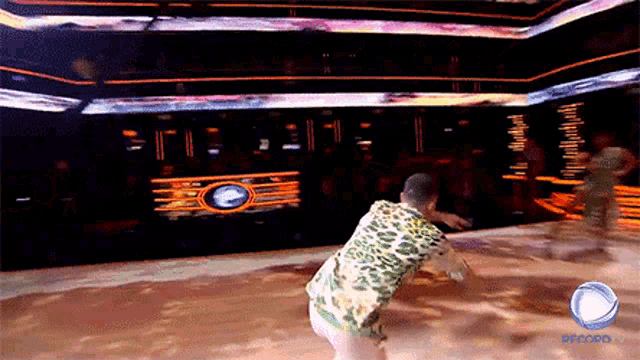 a man in a leopard print shirt is dancing on a stage with the word record on the bottom right