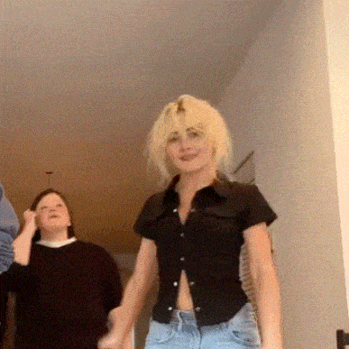 a woman in a black shirt and blue jeans is standing in a hallway .