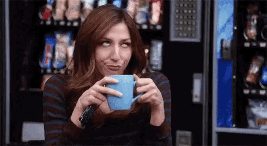 a woman is drinking a cup of coffee from a blue cup .