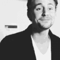 a black and white photo of a man wearing a jacket and a white shirt .
