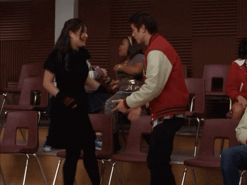 a man in a red jacket holds a woman 's hand