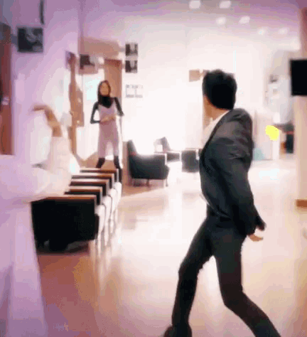 a man in a suit is dancing in a room with a woman in a white dress