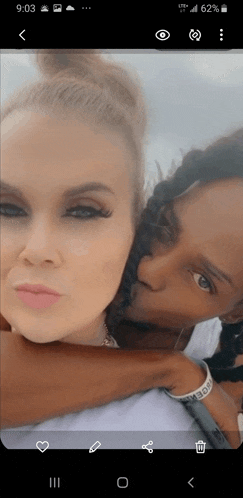 a phone screen shows two women hugging each other with the time 9:03