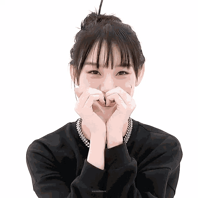 a woman is making a heart shape with her hands