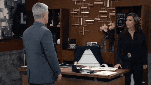 a man and a woman are standing in front of a desk with ad written on it