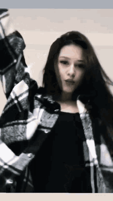 a woman wearing a plaid jacket and a black top