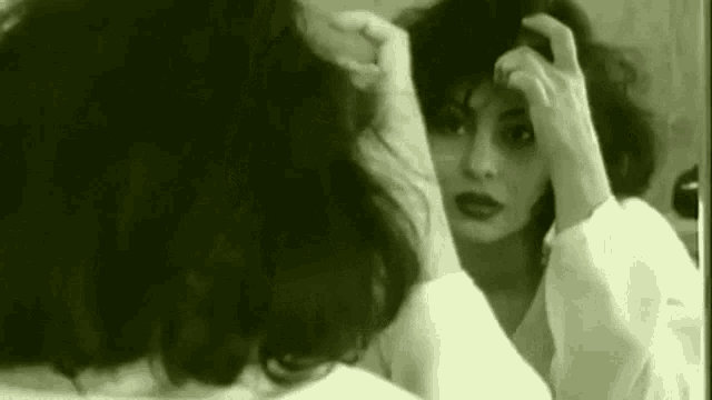 a woman is looking at herself in a mirror .