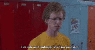 a young man wearing glasses and a yellow shirt is standing in front of a locker room .