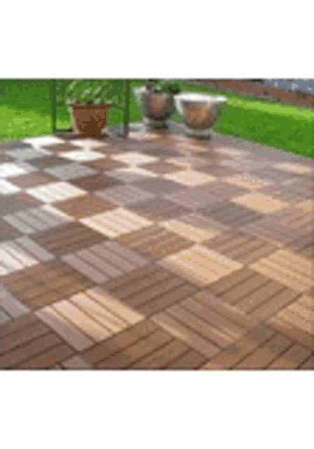 a patio with wooden tiles and potted plants on it