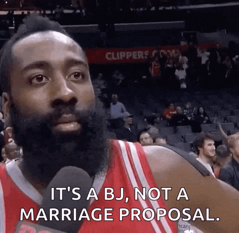 a basketball player with a beard is talking into a microphone while sitting in the stands at a basketball game .
