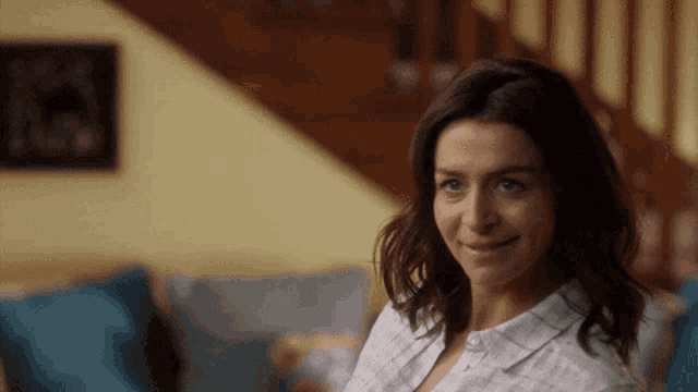 a woman in a plaid shirt smiles in front of stairs