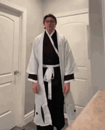 a man wearing a robe and glasses stands in front of a door