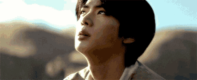 a close up of a man 's face with mountains in the background