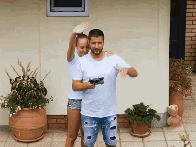 a man and a woman are standing in front of a house