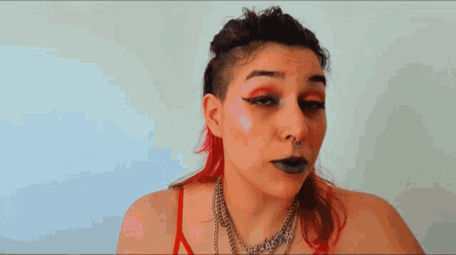 a woman with red hair and a nose ring has a red top on