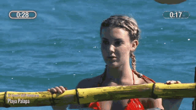 a woman in a red bikini is swimming in the ocean with a timer behind her that says 0:17