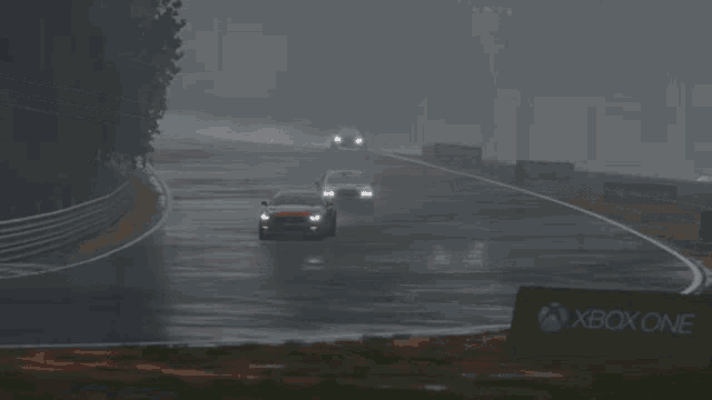 a red car is driving down a wet road next to a sign for xbox