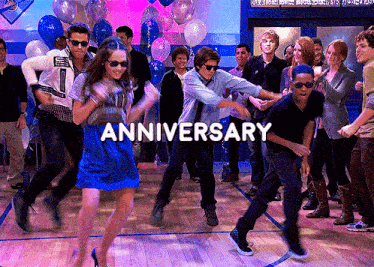 a group of people are dancing in front of balloons and the words anniversary