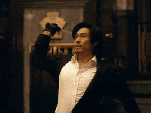 a man in a suit and white shirt is holding a knife in his right hand