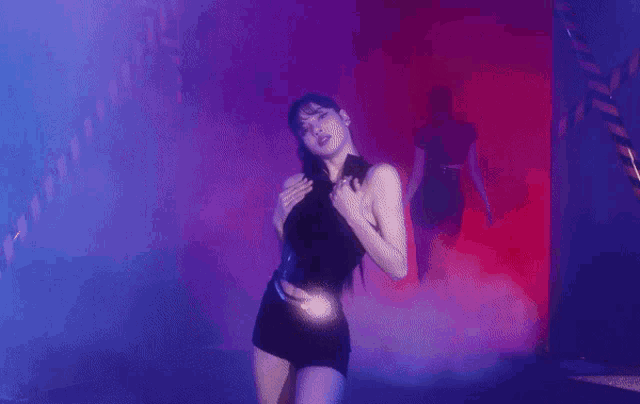 a woman is dancing in a dark room with smoke coming out of the doorway .