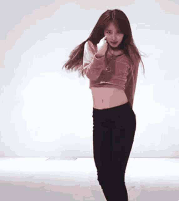 a young woman in a crop top and black pants is dancing