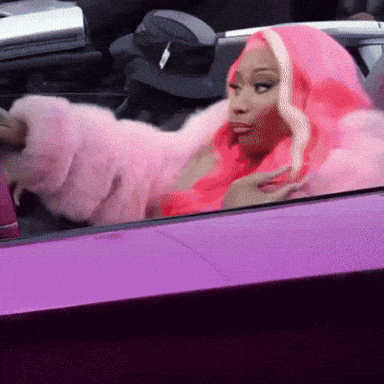 a woman with pink hair is sitting in a purple car .