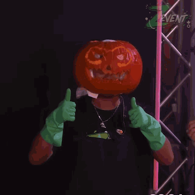 a man with a carved pumpkin on his head gives a thumbs up