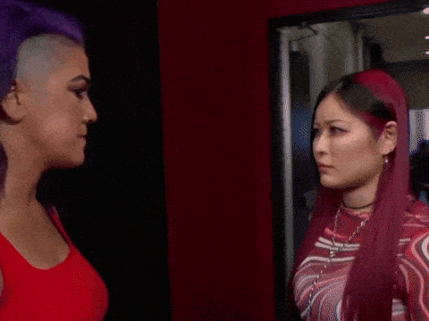 two women with purple hair are standing next to each other looking at each other .